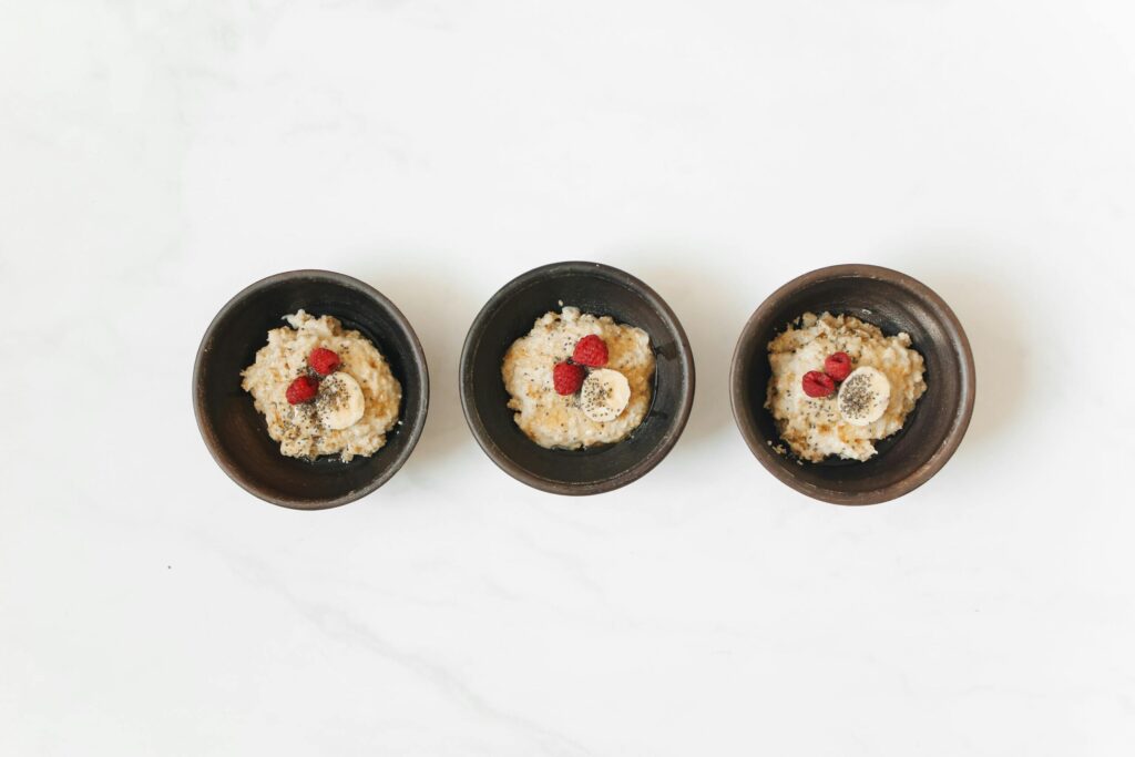 Delicious breakfast bowls with oatmeal, banana, and raspberries on a clean white background.